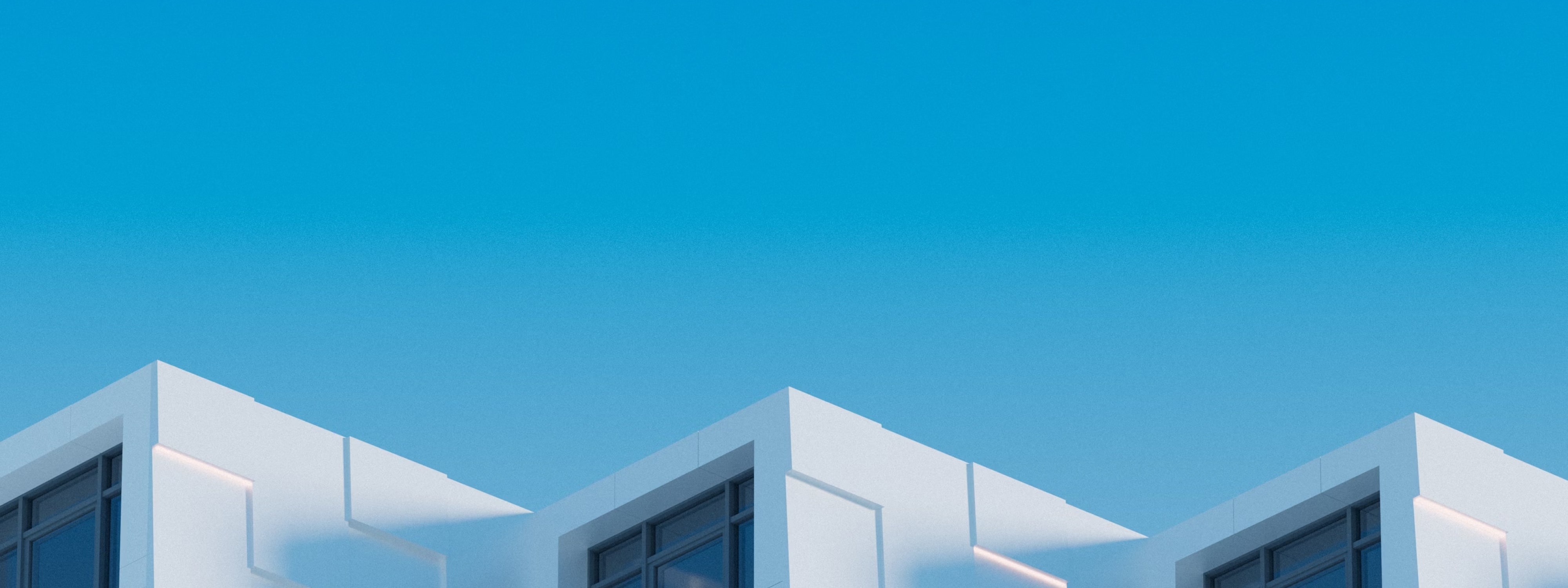 White modern buildings with large windows against a clear blue sky